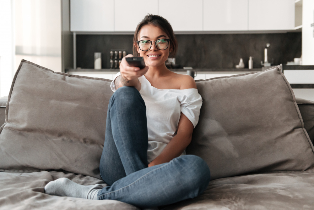 happy young woman sitting sofa home watch tv